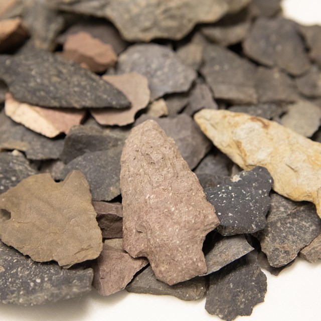 A variety of differently sized, shaped and colored chips of stone and projectile points.