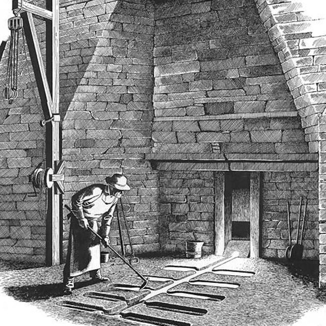 A person standing in front of a brick structure holding a rake-like object over several troughs.
