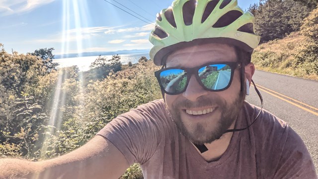 Man taking a selfie on a bike, wearing a bike helmet and sunglasses