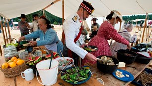 Reenactors helping themselves to a buffet of historically accurate foods.