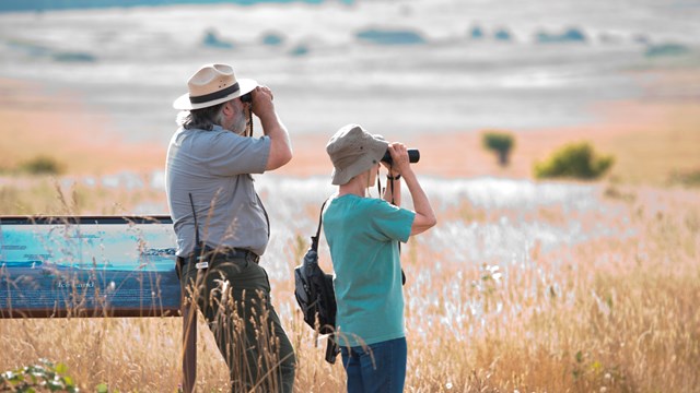 Ranger and park visitor using binoculars.