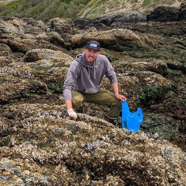 Color photo of a man foraging in colorful tidepools