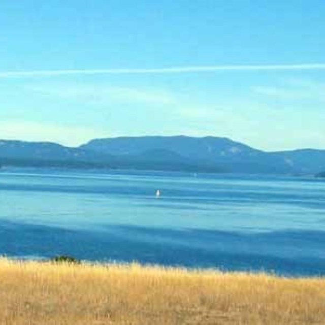 A mountain viewed across the water from a prairie