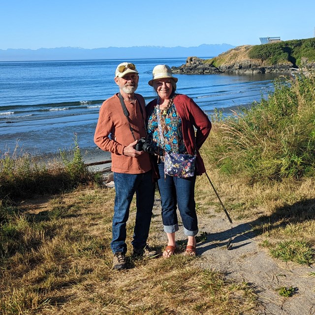 A man and a woman on a hiking trail overlooking the ocean
