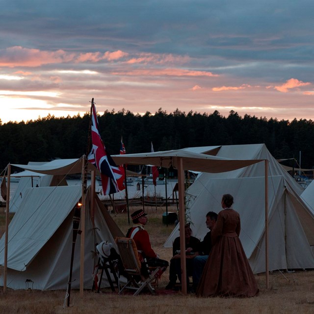 Reenactors on parade grounds at dusk.