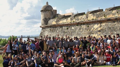 A large group of volunteers and NPS Staff pose for a photo in front of El Canuelo
