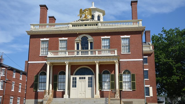 A brick building with a large sign over the main door. The sign says CUSTOM HOUSE