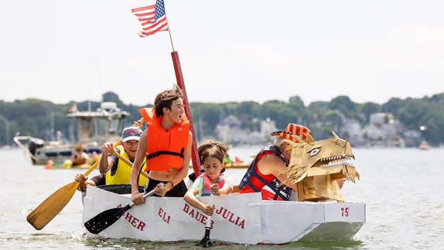 A group in a decorated cardboard boats race in a harbor
