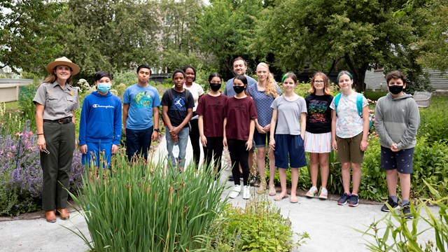 Students and park ranger standing in a garden.