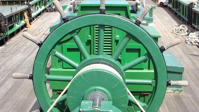 bright green steering system with wheel on top deck of sailing vessel