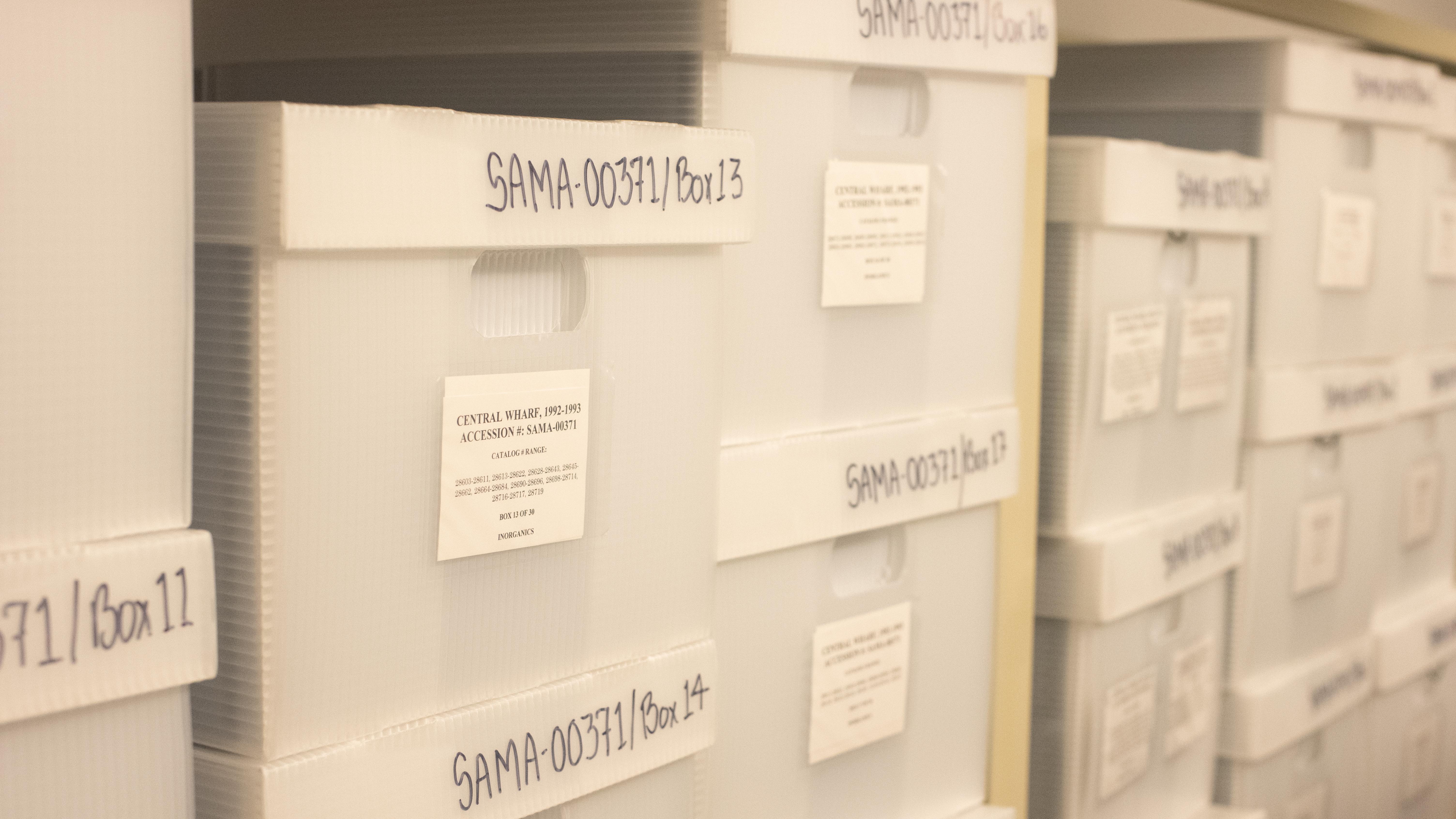 Stacks of white storage boxes with labels.