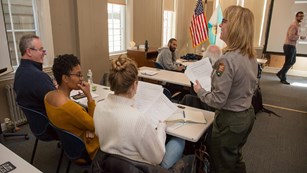 Park Ranger speaks with three adults seated at a table.