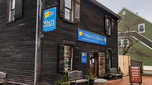 two story wooden building with blue sign reading Waite & Peirce