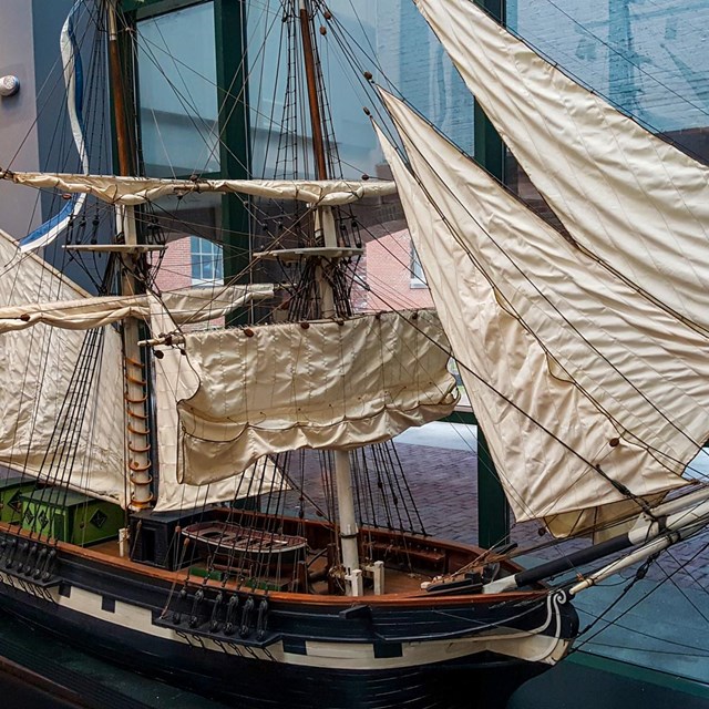a three-masted model ship with white sails