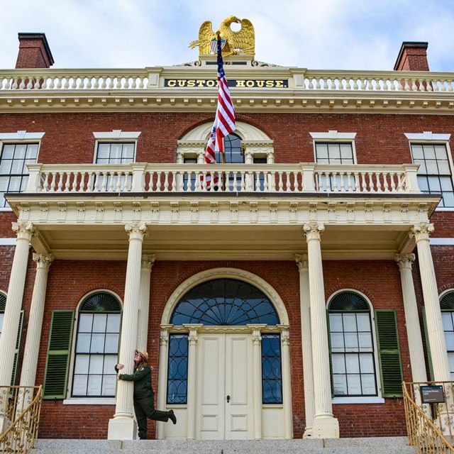 Two story brick building with white columns and gold eagle on roof