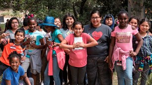 A group of students stand side-by-side and smile at the camera