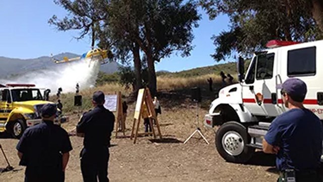 A helicopter spraying the ground with onlookers.