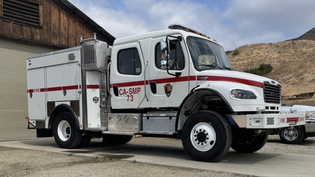 White fire truck parked in concrete driveway.