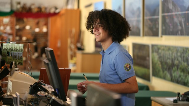 Young person behind the desk with a blue volunteer shirt on.