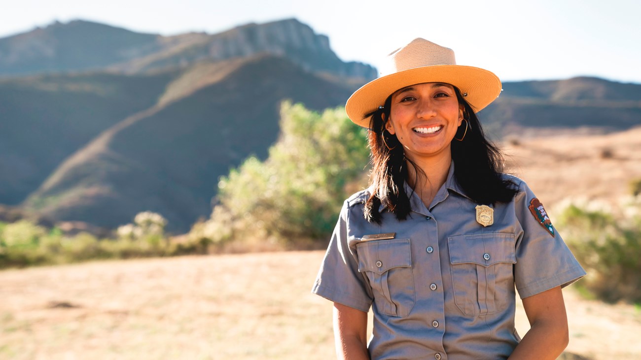 Ranger smiling in front of mountains.