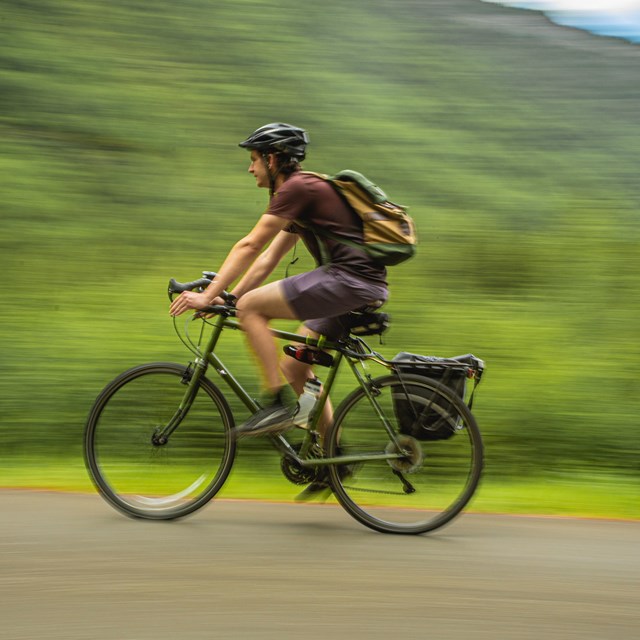 a man wearing a helmet bicycles on a path