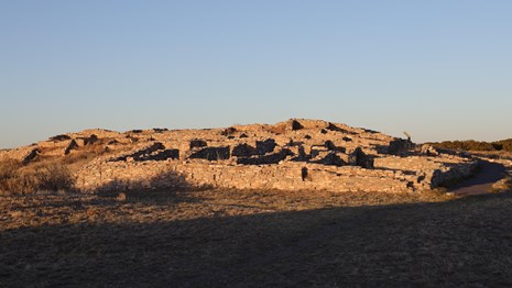 Grey limestone pueblo ruins in the evening sun.