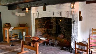 Kitchen scene with wooden tables and a brick fireplace in the background