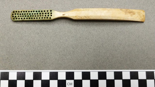 Ivory toothbrush missing its bristles, black and white checkered guide on bottom