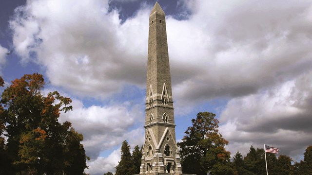 The Saratoga Monument with partly cloudy skies behind it