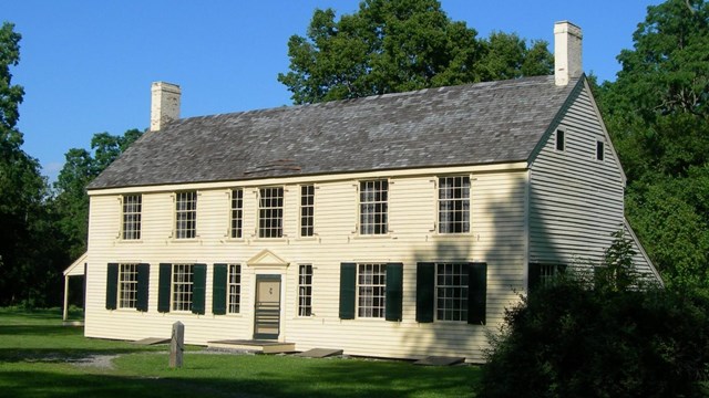 A yellow house sits among green vegetation.