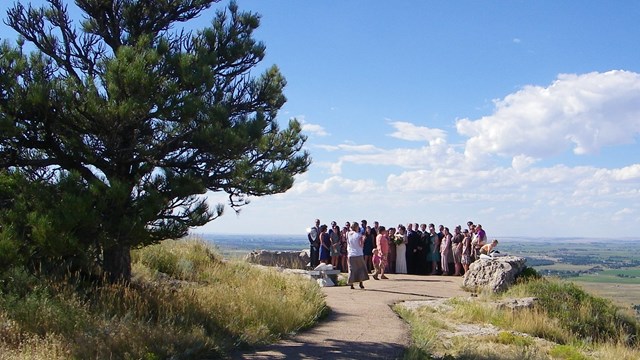A group of people is gathered at an overlook for a wedding ceremony. 