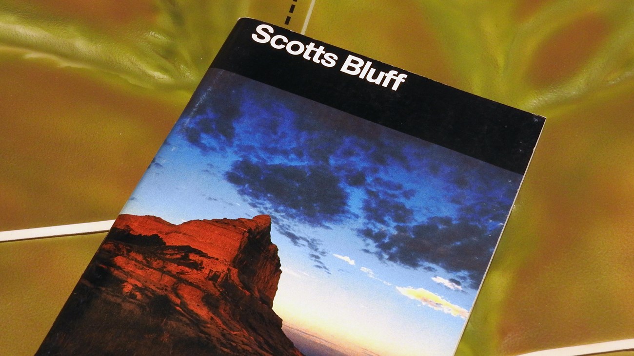 A book titled "Scotts Bluff", rests on a section of three-dimensional map.
