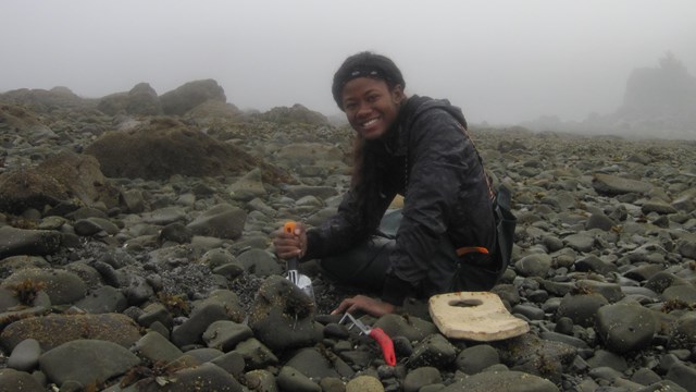 Image of woman sitting in a rocky field with hand tools