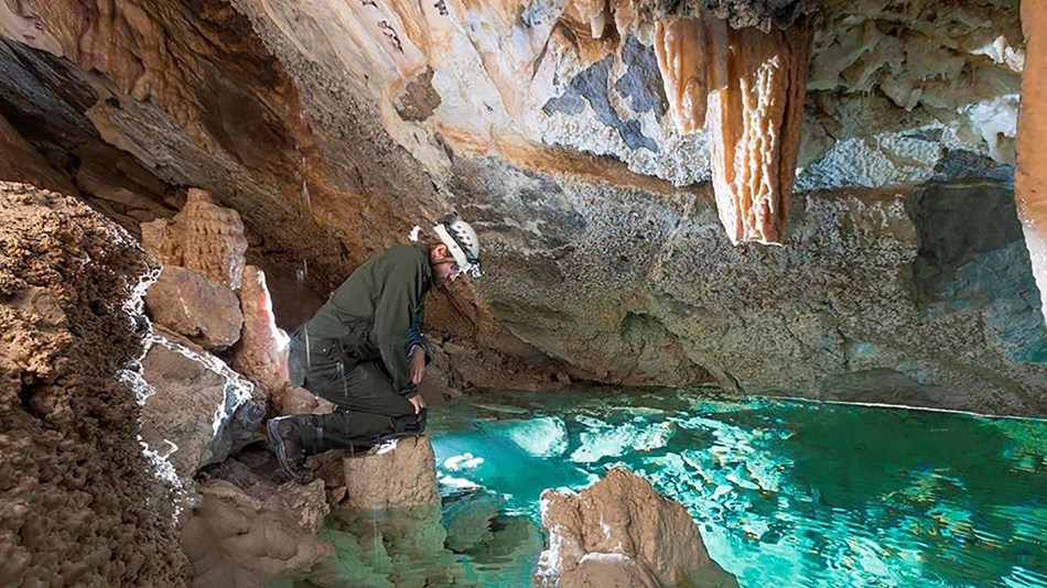 A man peers into a lake in a cave.