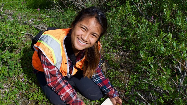 Image of an individual smiling while taking measurements on the ground