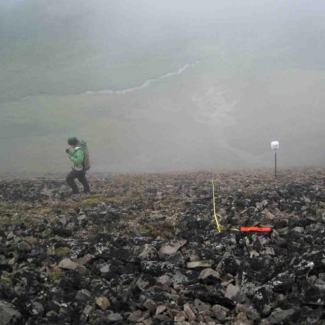 A researcher on a steep slope collecting vegetation data.