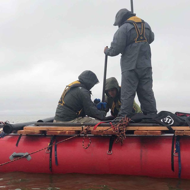 Researchers in an inflatable boat collect sediment cores from a lake.