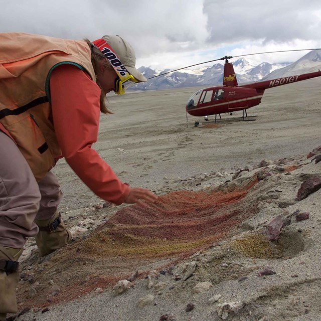 A geologist looks at volcanic soil on a volcano.