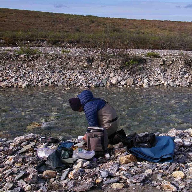 A scientist collects data on an Arctic stream.