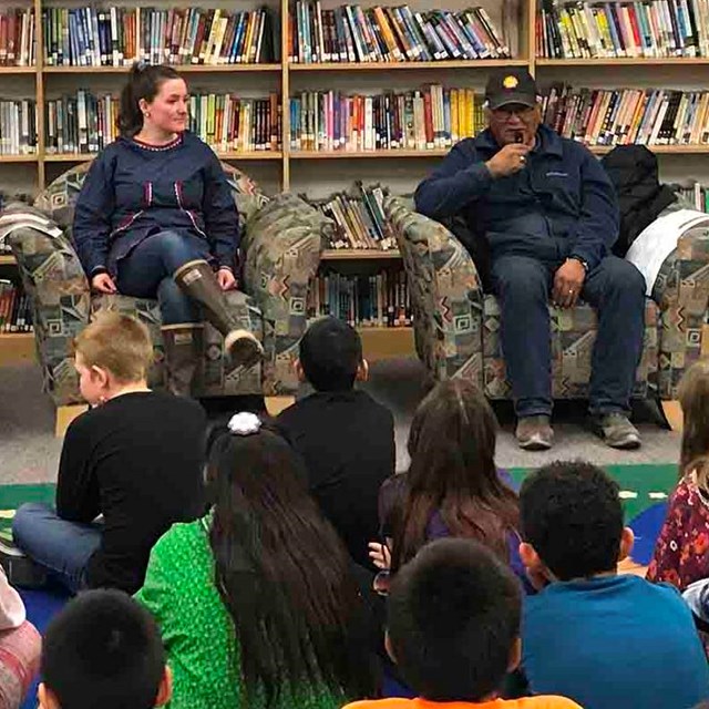 Elders speak to an audience of youth in a library.