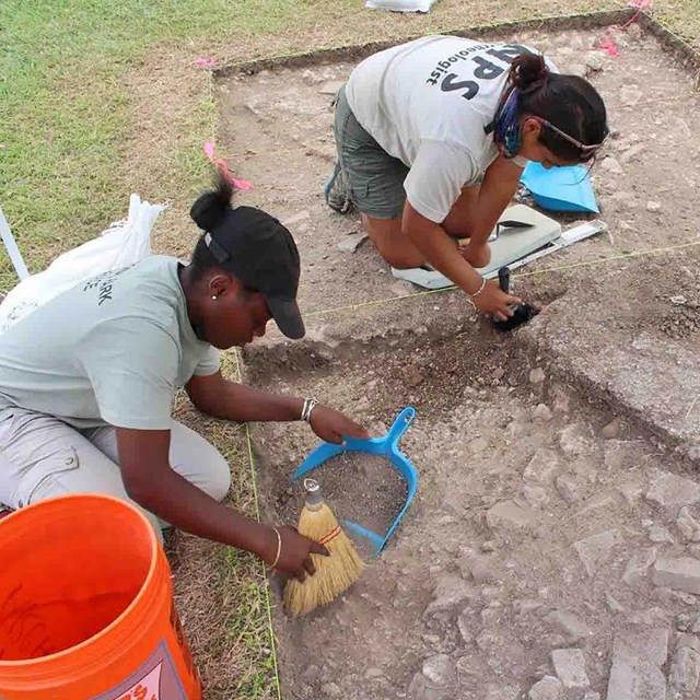 Two young women of color work on an excavation.