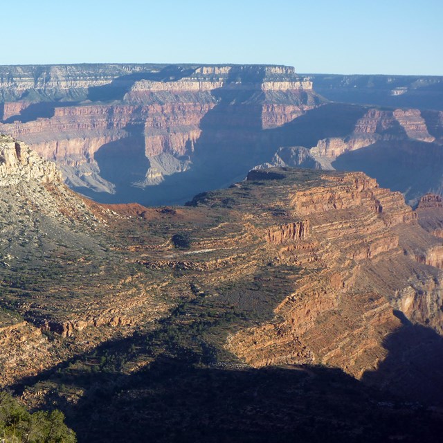 Rock formation in the foreground with sunlit canyon walls in the background.