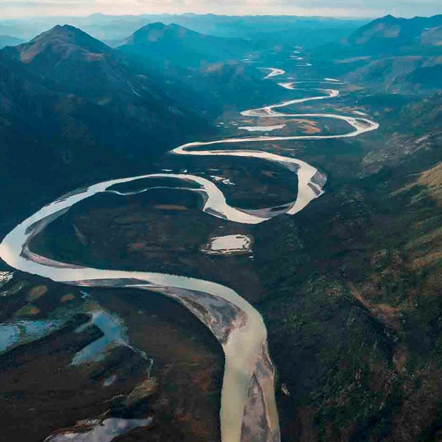 A river winds through a valley surrounded by steep mountains.