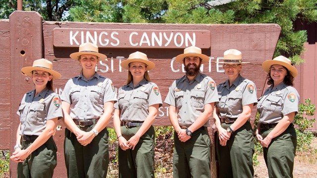 A group of ranger staff posing in front of the King Canyon entrance sign.