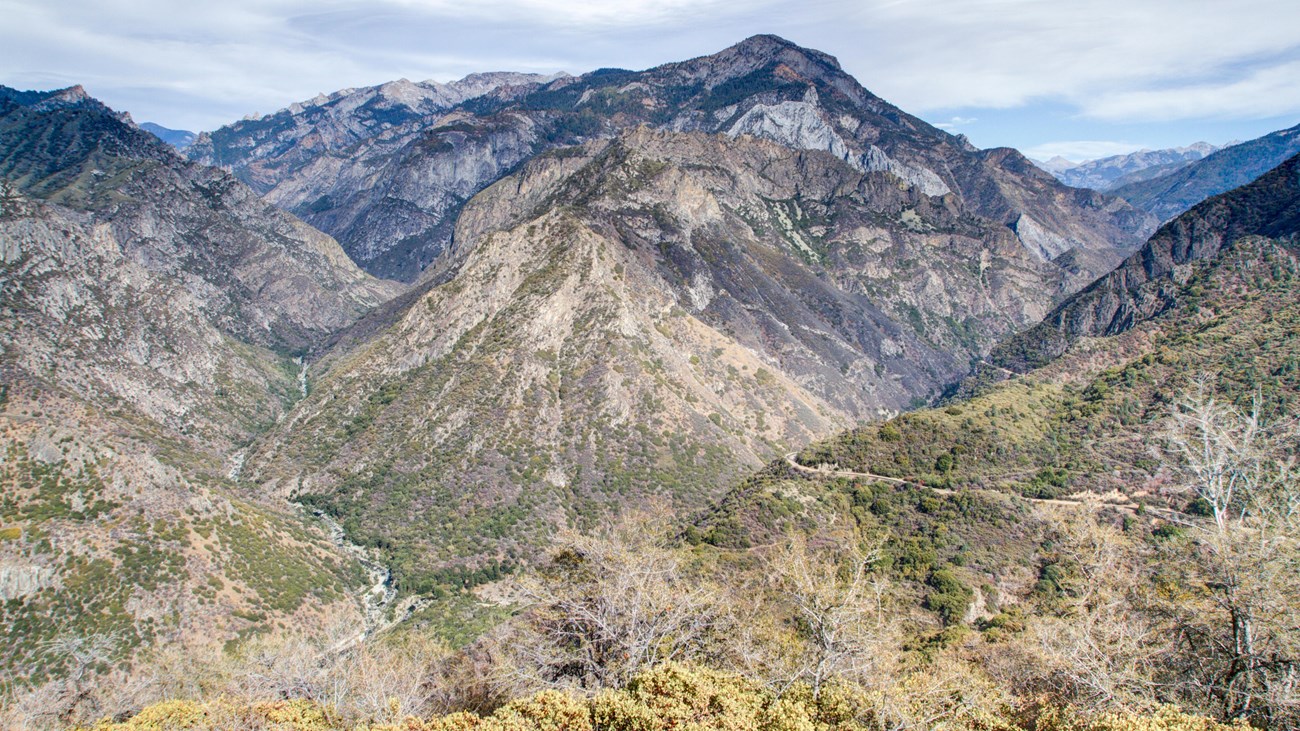 A large canyon view overlooking a road alongside a river.