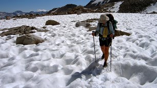 A hiker crossed a pitted snowfield