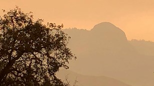 Smoke darkens the sky and obscures views of distant ridges