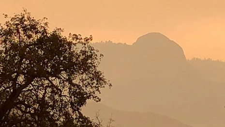 Smoke darkens the sky and obscures views of distant ridges