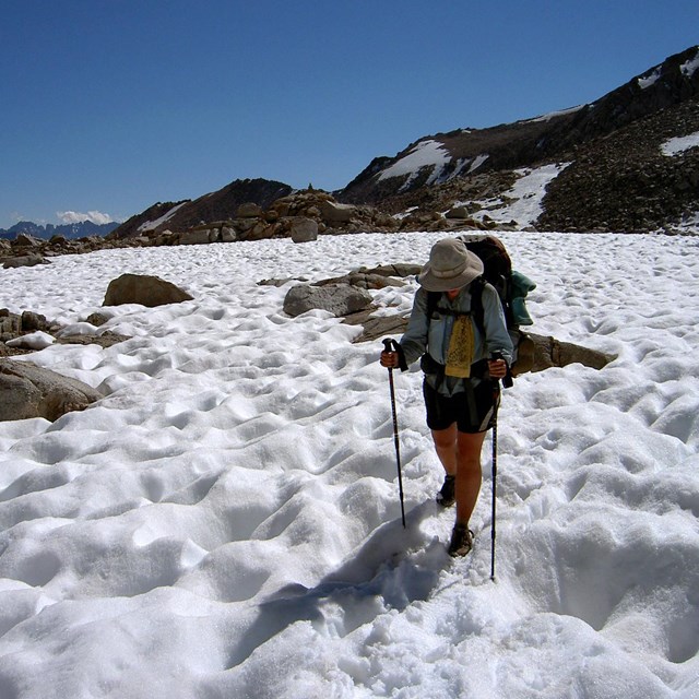 A hiker crossed a pitted snowfield