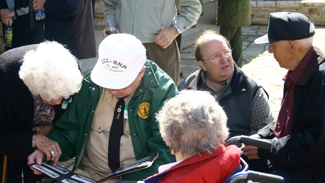 A color photograph of a group of people looking at old photo albums.